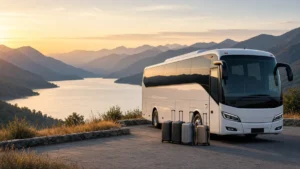 Ônibus de turismo estacionado diante de mirante com montanhas e lago ao entardecer, com malas ao lado, ilustrando marketing para viagens em grupo